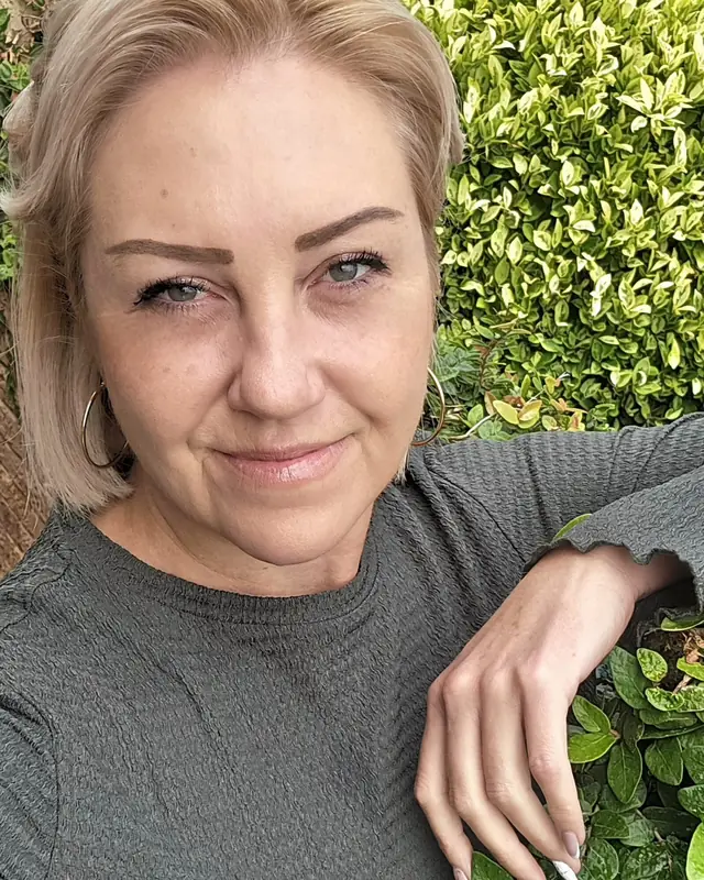 Elizabeth Holland smiling warmly among green leaves