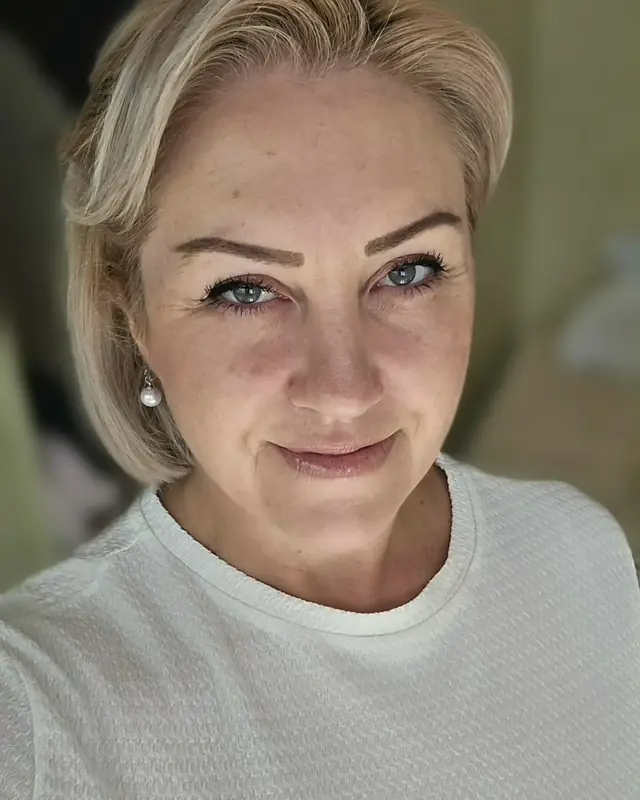Elizabeth Holland smiling warmly, wearing a white top